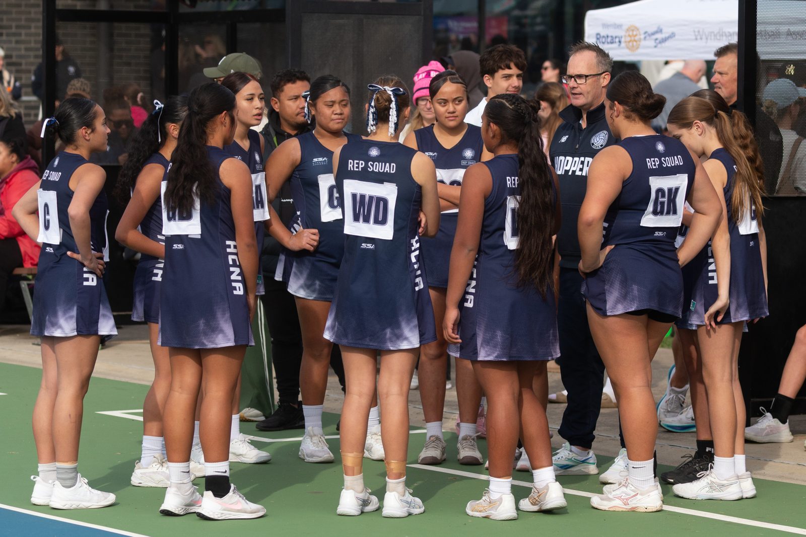 HCNA representative squad gathered courtside listening to their coach at a Wyndham community netball event