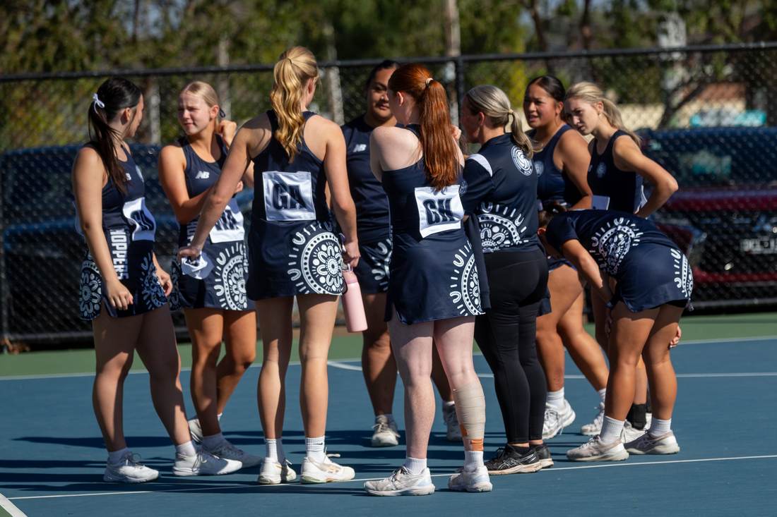 Hoppers team in a huddle wearing the Indigenous-design dress